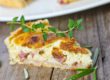 Quiches. Ein Stück Quiche Lorraine garniert mit Thymian und Rosmarin..